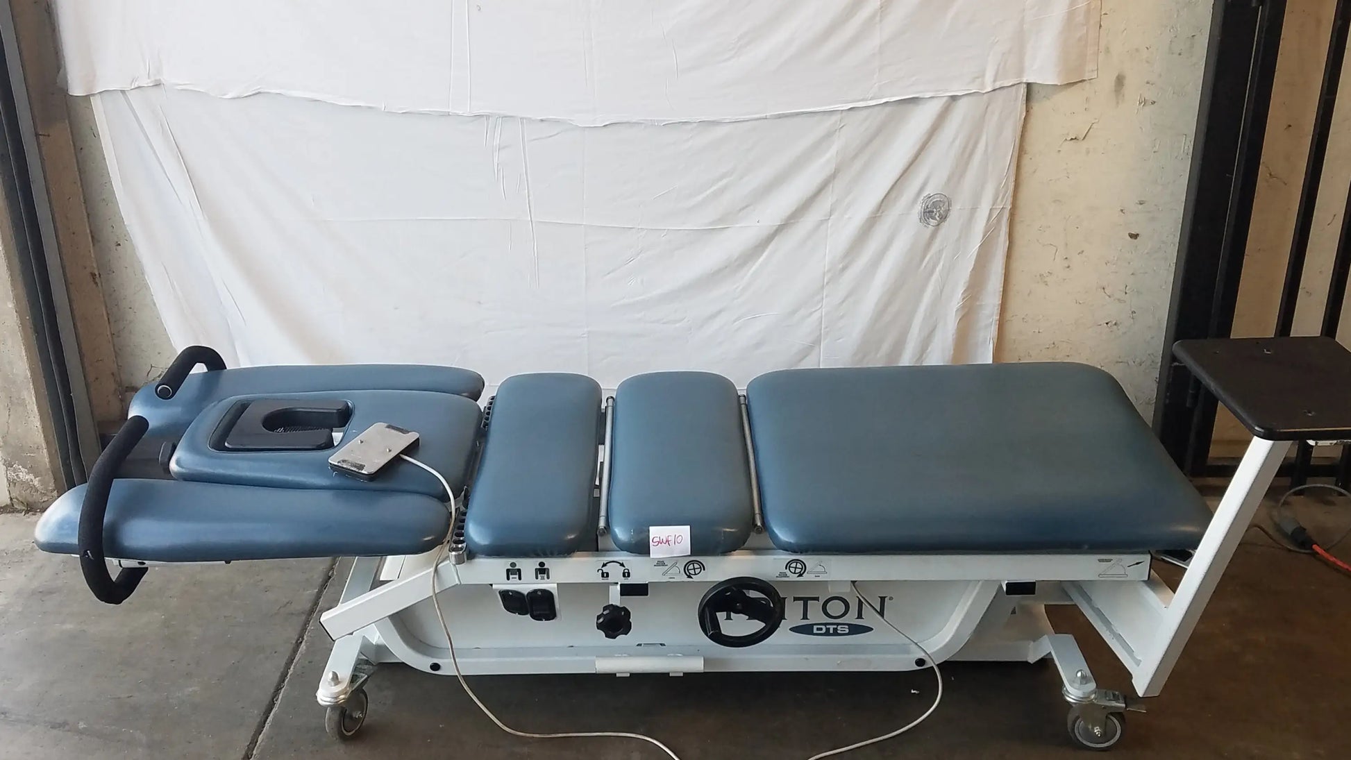 Blue padded adjustable Chattanooga trt-600 triton dts table with white metal frame and casters for physical therapy equipment
