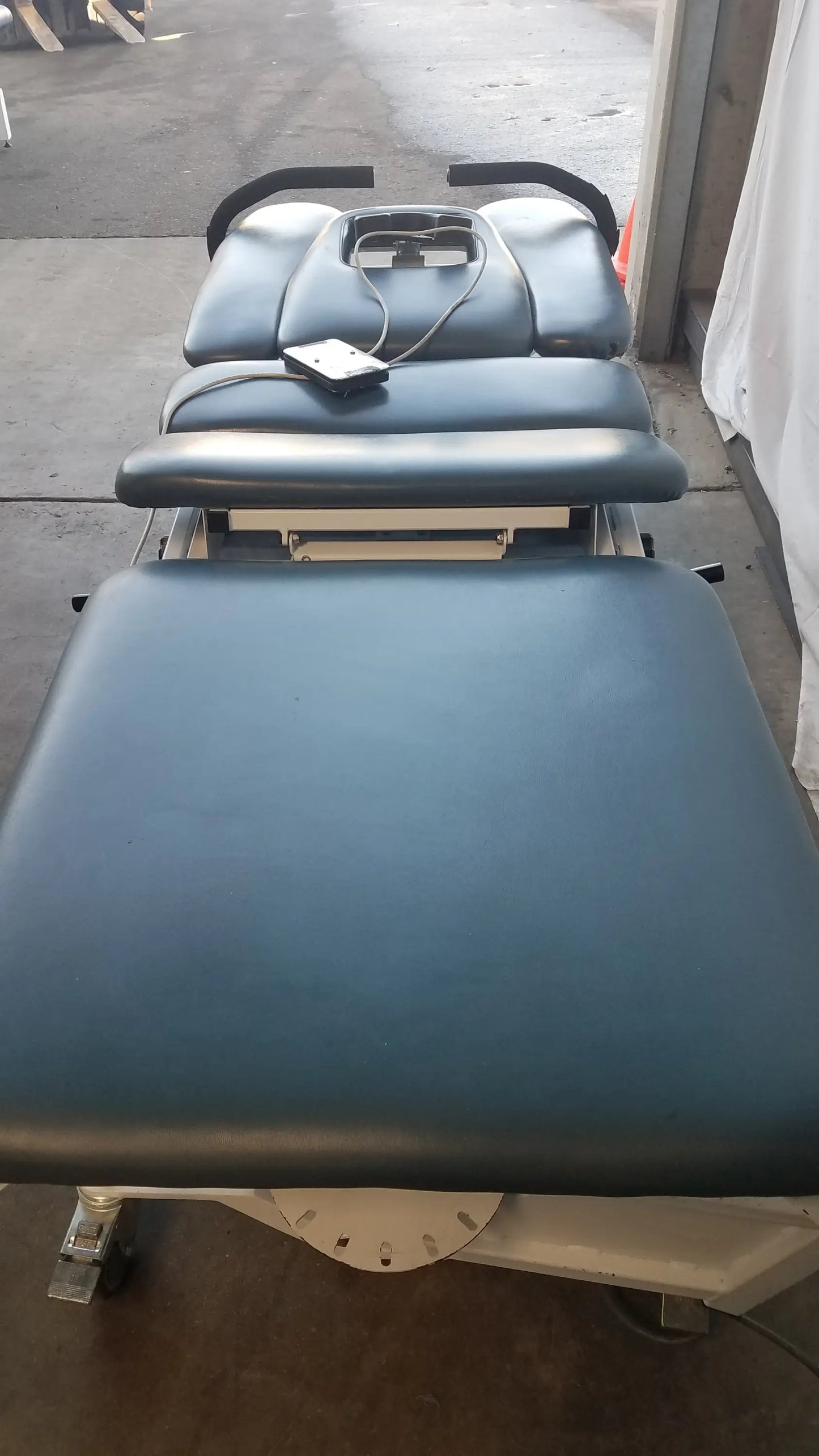 Blue padded Chattanooga TRT-600 Triton DTS traction table with adjustable sections and black armrests for physical therapy equipment