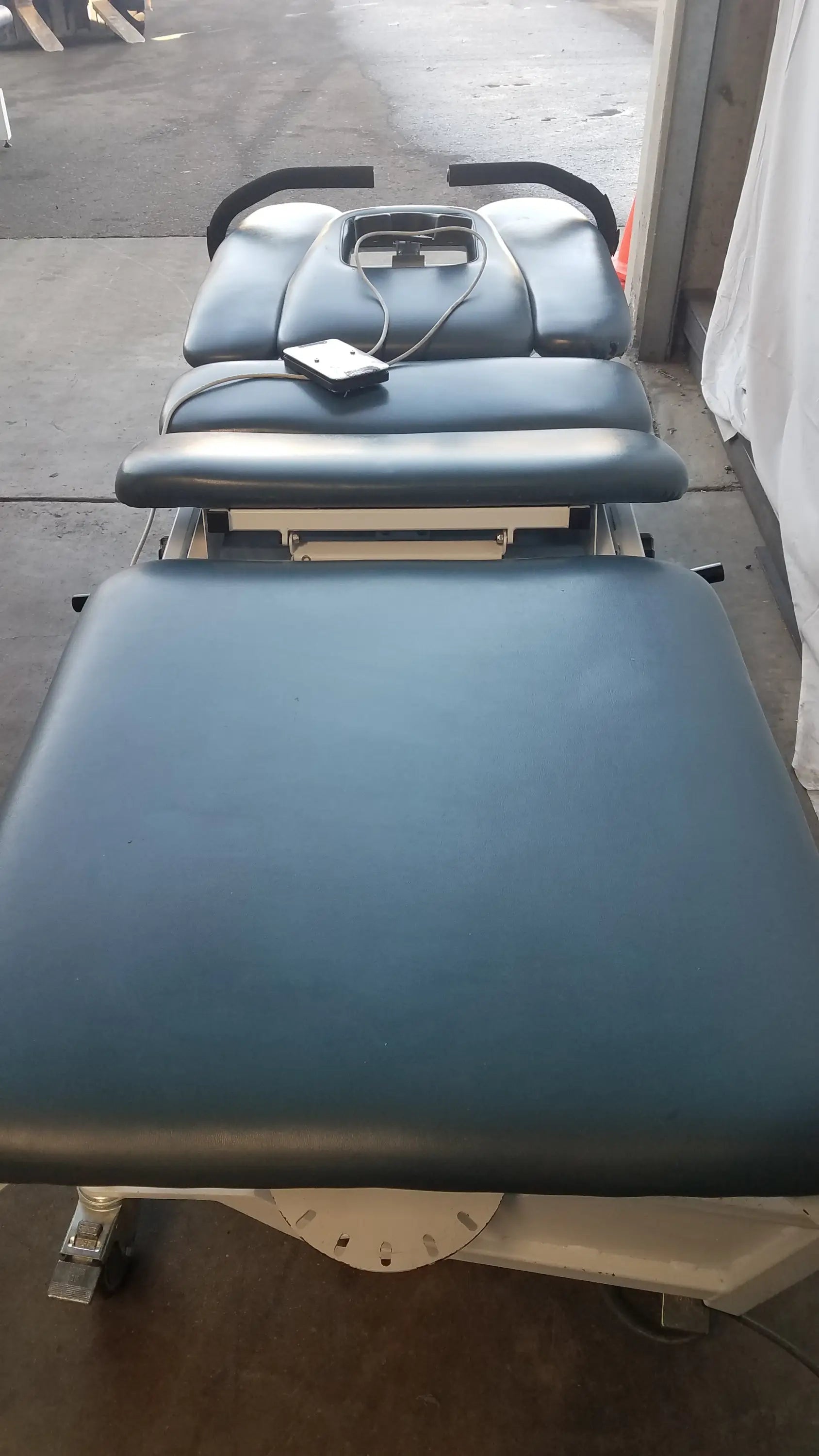 Blue padded Chattanooga TRT-600 Triton DTS traction table with adjustable sections and black armrests for physical therapy equipment
