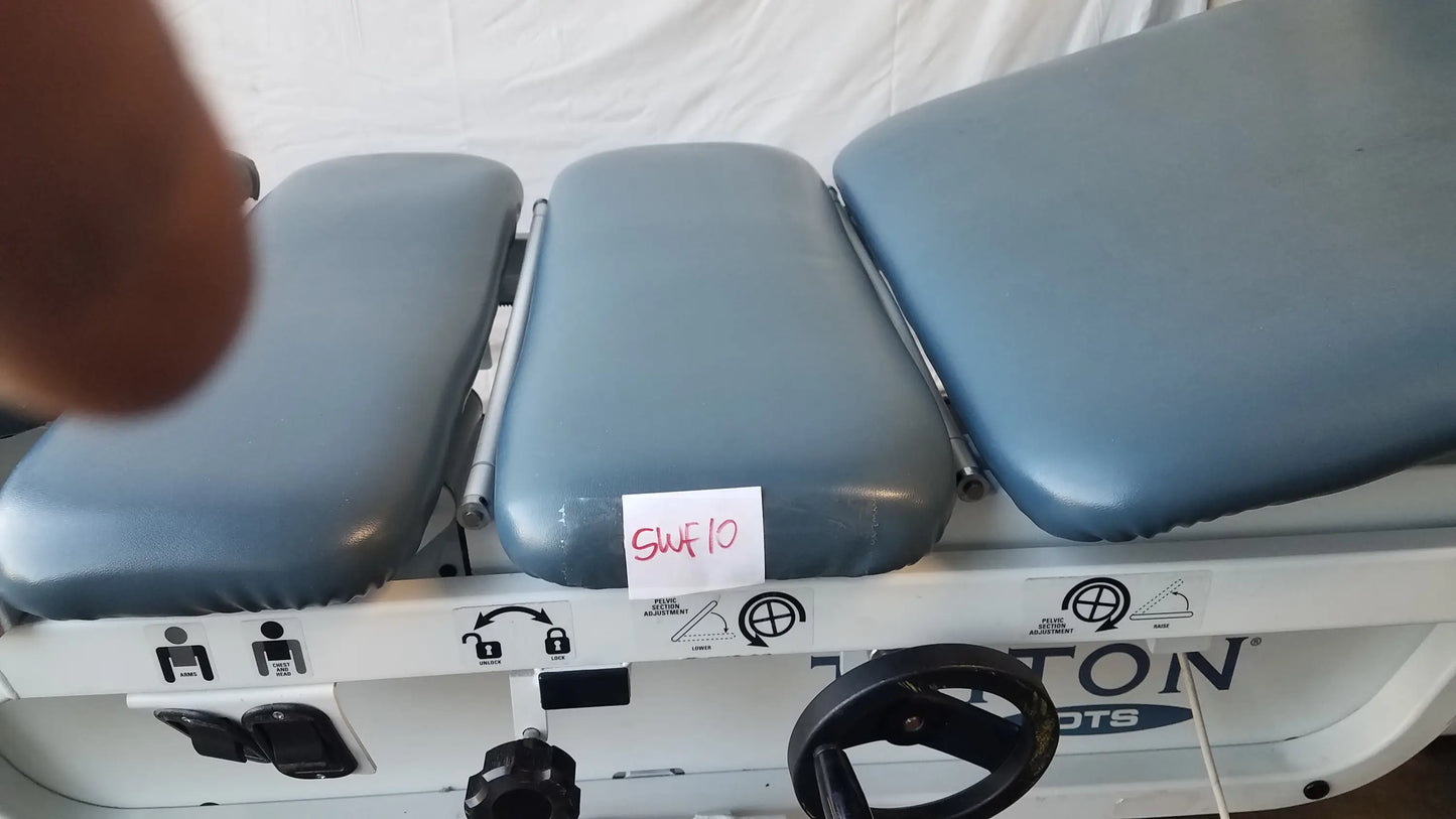 Gray padded three-section adjustable triton dts table with white metal frame and black control wheel for physical therapy equipment
