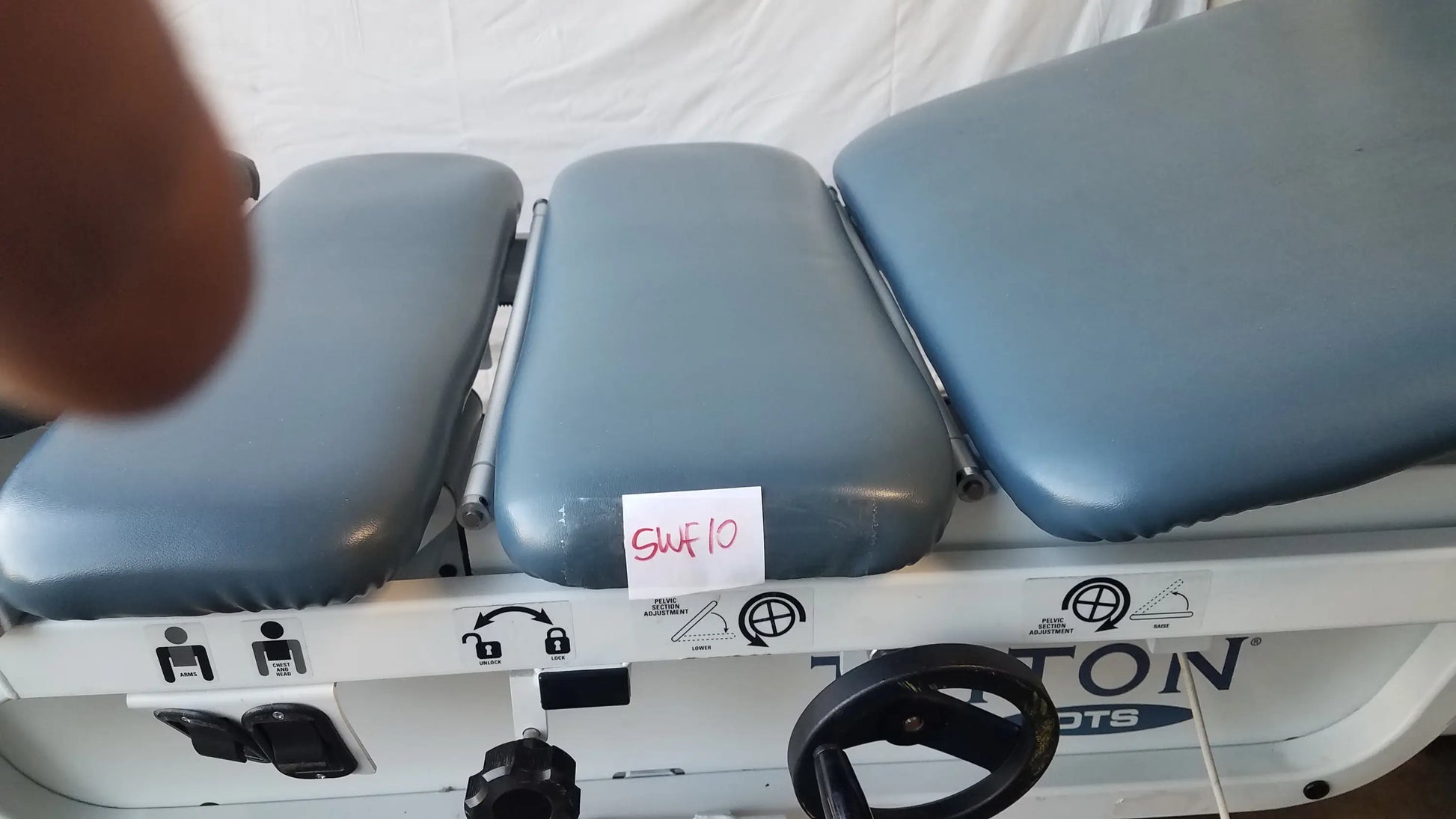 Gray padded three-section adjustable triton dts table with white metal frame and black control wheel for physical therapy equipment