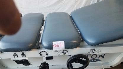 Gray padded three-section adjustable triton dts table with white metal frame and black control wheel for physical therapy equipment