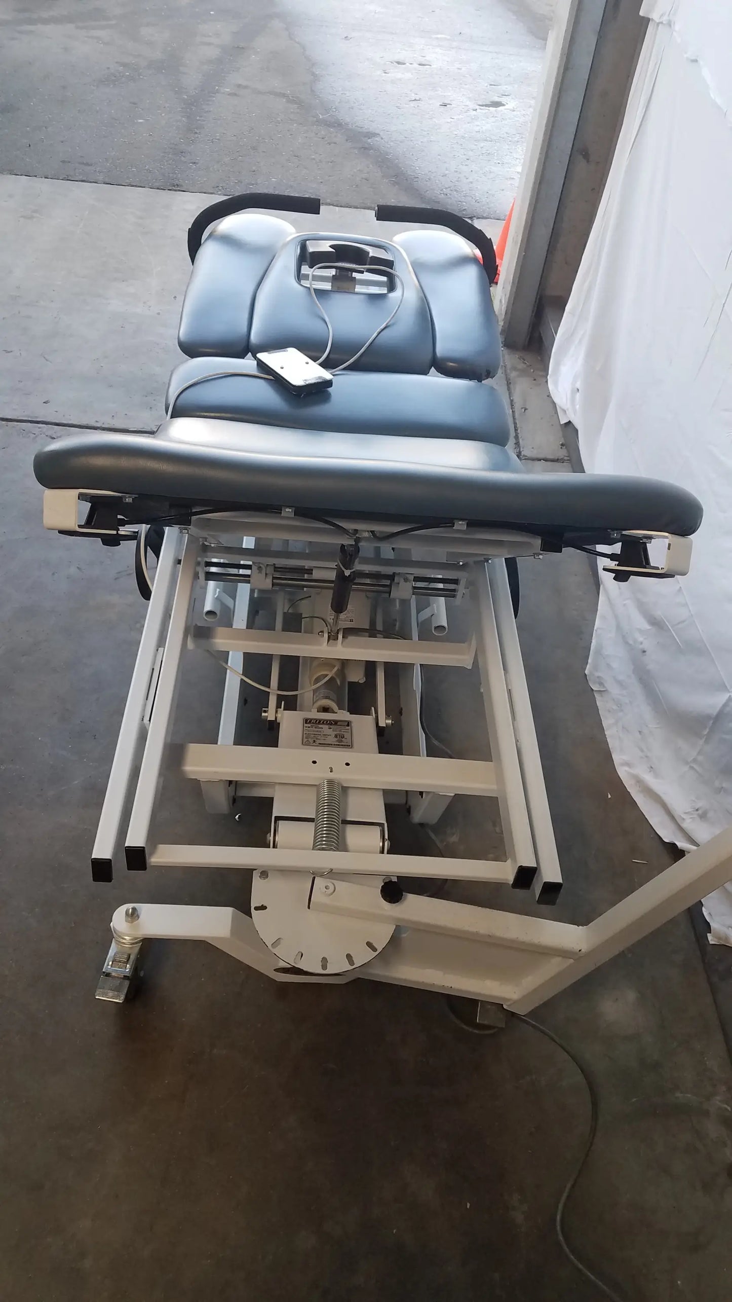 Adjustable Chattanooga TRT-600 Triton DTS traction table with blue and black padded upholstery and metal frame for physical therapy equipment