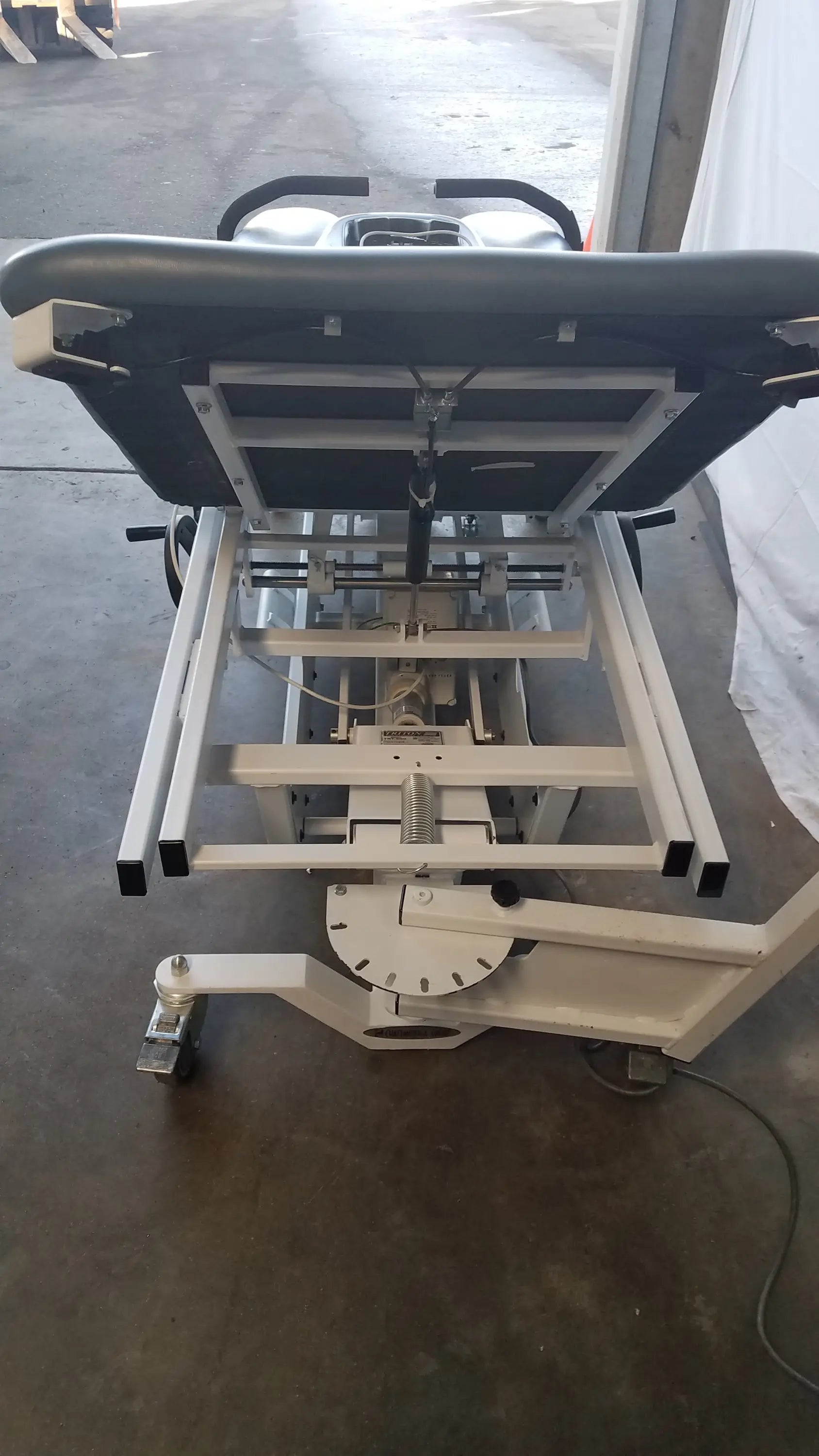 Medical-grade adjustable patient lift with black padded headrest and white metal frame for triton dts physical therapy equipment
