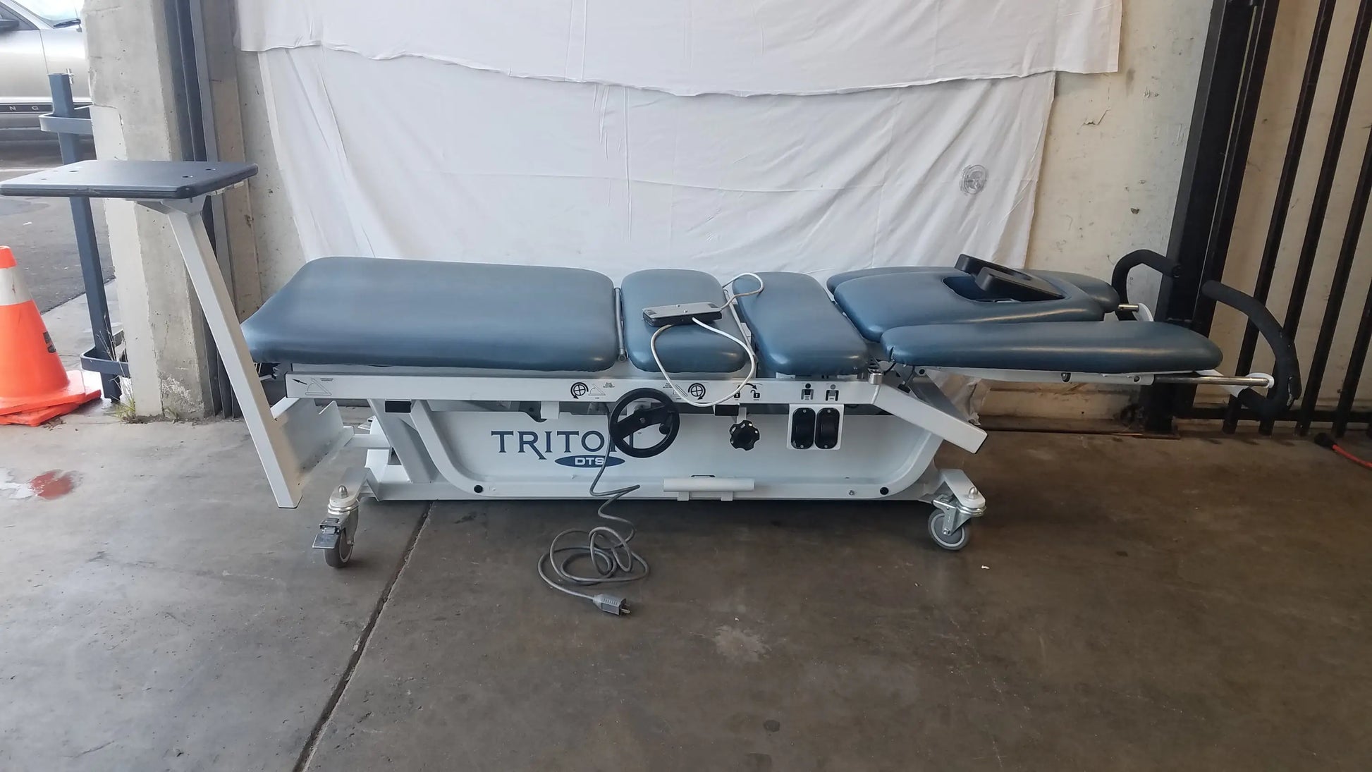 Gray upholstered adjustable Chattanooga TRT-600 Triton DTS traction table with white metal frame for physical therapy equipment