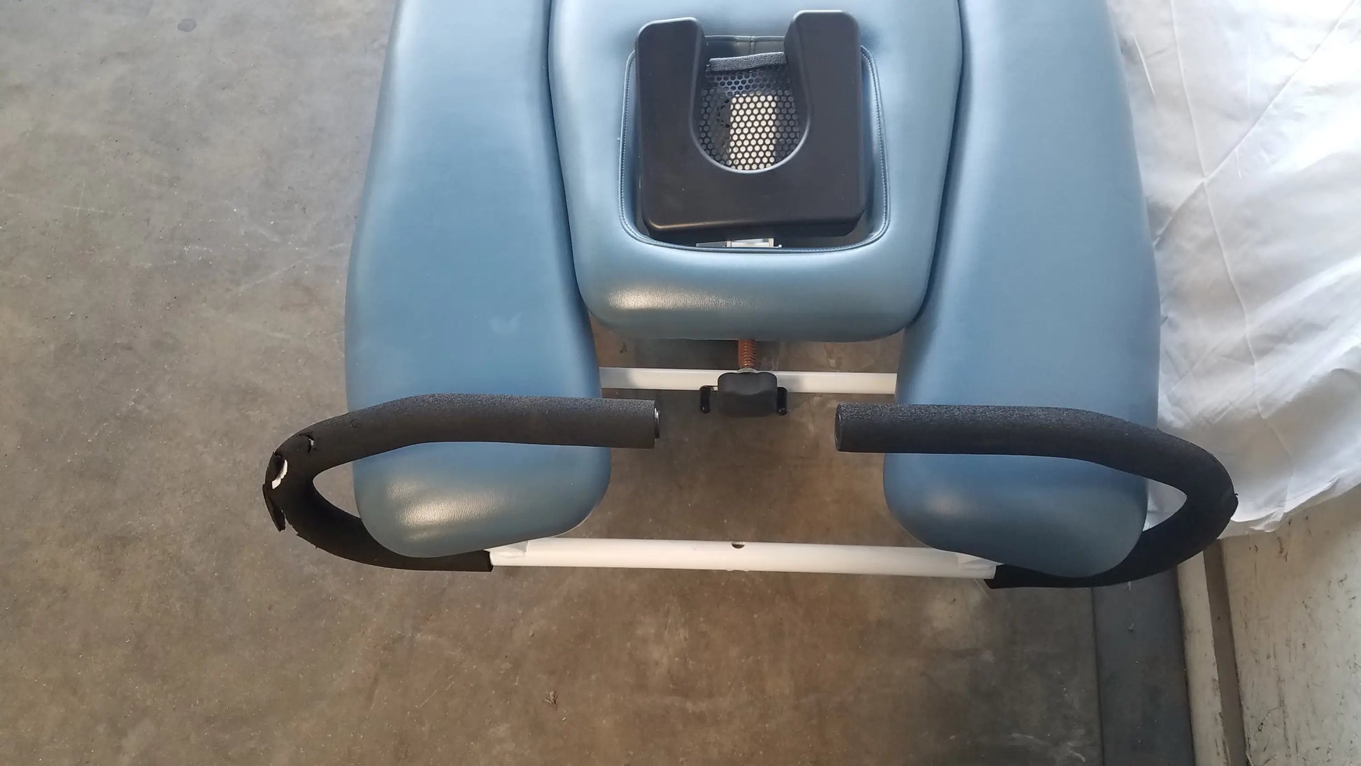 Light blue padded therapy chair with black rubberized armrests and mesh adjustment on triton dts table for physical therapy equipment