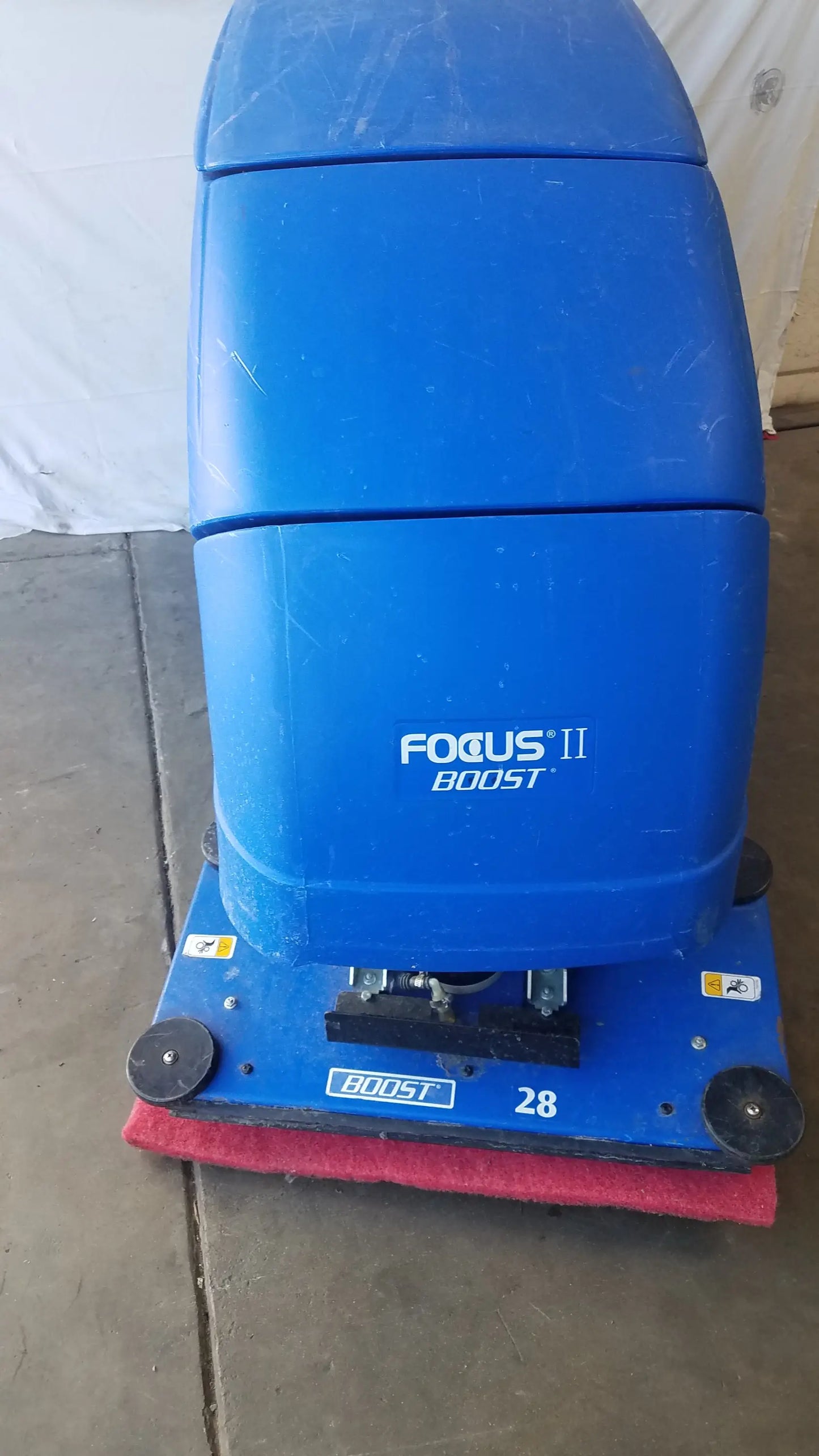 Clarke focus ii boost floor scrubber in blue plastic with red scrubbing pad and black wheels for floor cleaning