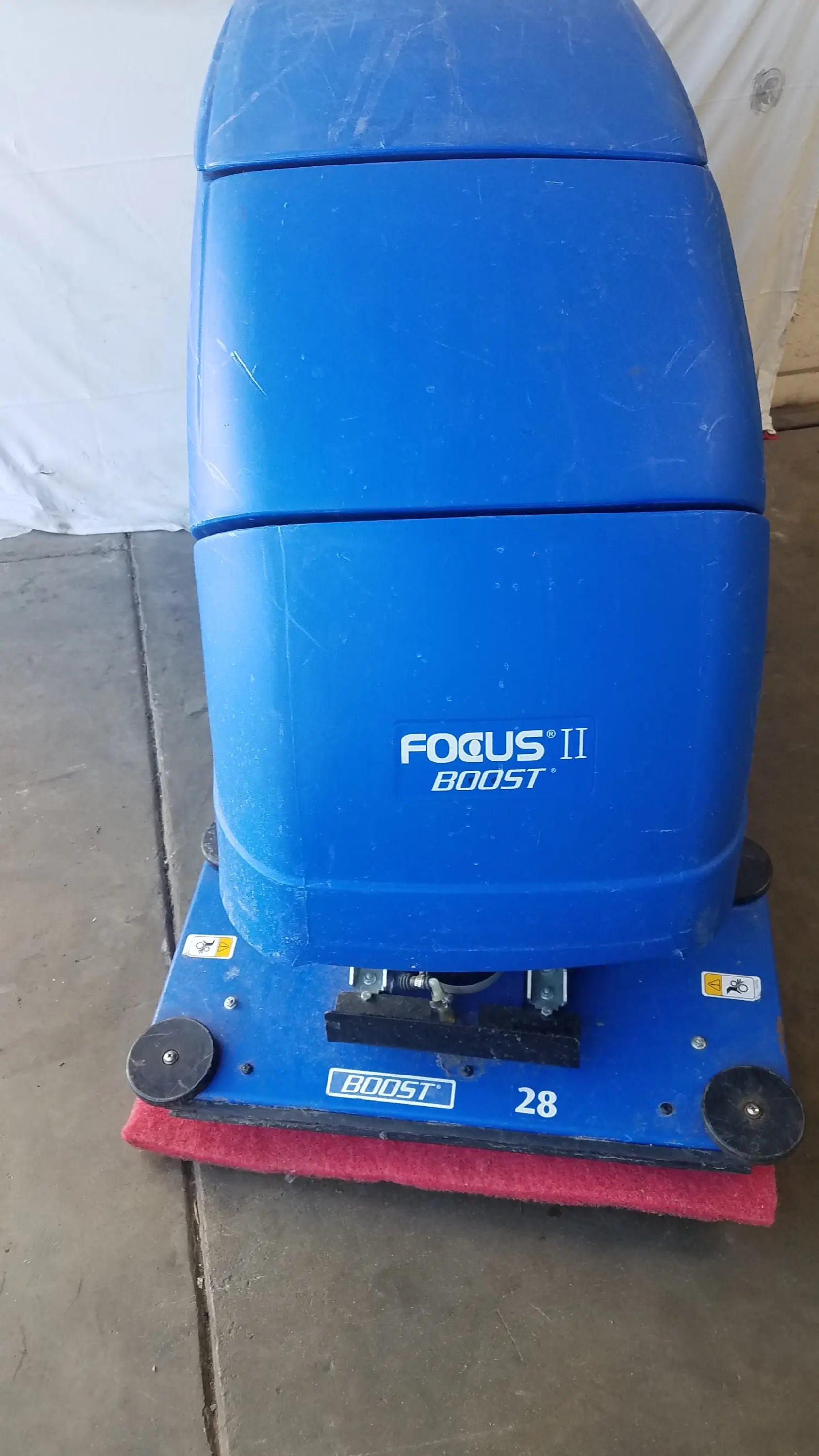 Clarke focus ii boost floor scrubber in blue plastic with red scrubbing pad and black wheels for floor cleaning