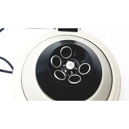 Cream vintage-style rotary telephone with black dial and silver number rings shown with clay adams roche model analytical centrifuge