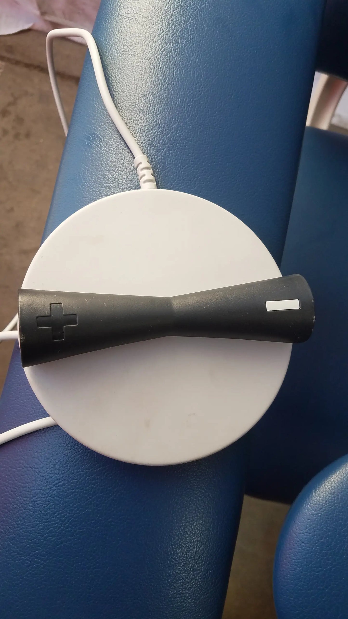 Black handheld dental scanner with plus sign on charging base for clinton 6341 power series blood drawing chair