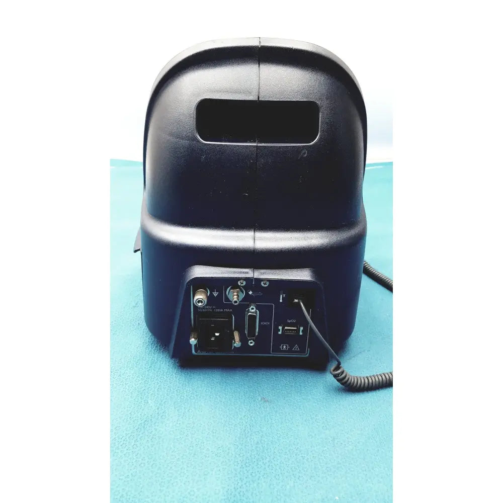Black plastic audio mixer with multiple ports and coiled cable at the back of colin press-mate prodigy ii 2240 patient monitor