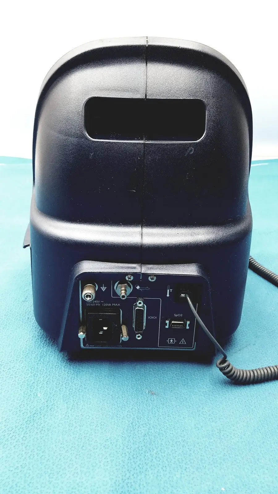 Black plastic audio mixer with multiple ports and coiled cable at the back of colin press-mate prodigy ii 2240 patient monitor