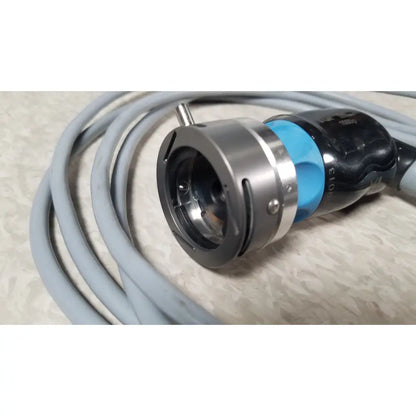 Silver metallic camera lens mount with blue and black housing wrapped in gray cable of conmed im4123 true hd 1080p urology camera head