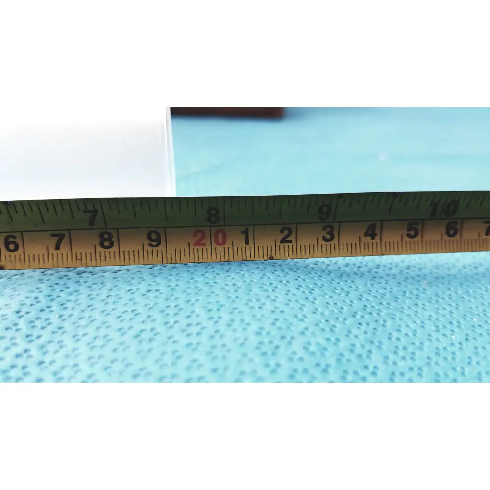 A yellow plastic ruler with black and red markings on a blue surface alongside corning laboratory glassware ground joint adapter