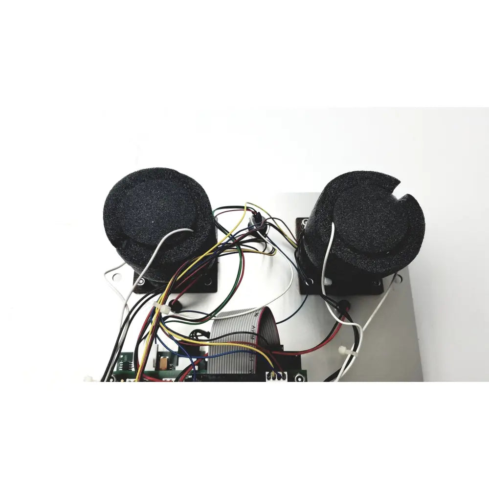 Black circular speakers with textured surfaces on circuit board with colorful wires in covidien genius 2 checker calibrator