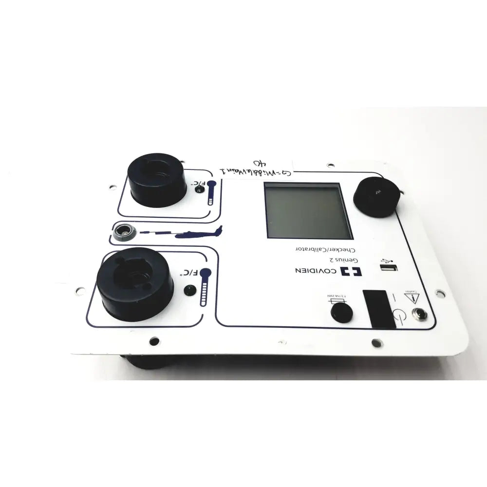 White plastic covidien genius 2 checker calibrator with black circular components and central digital display for test meters