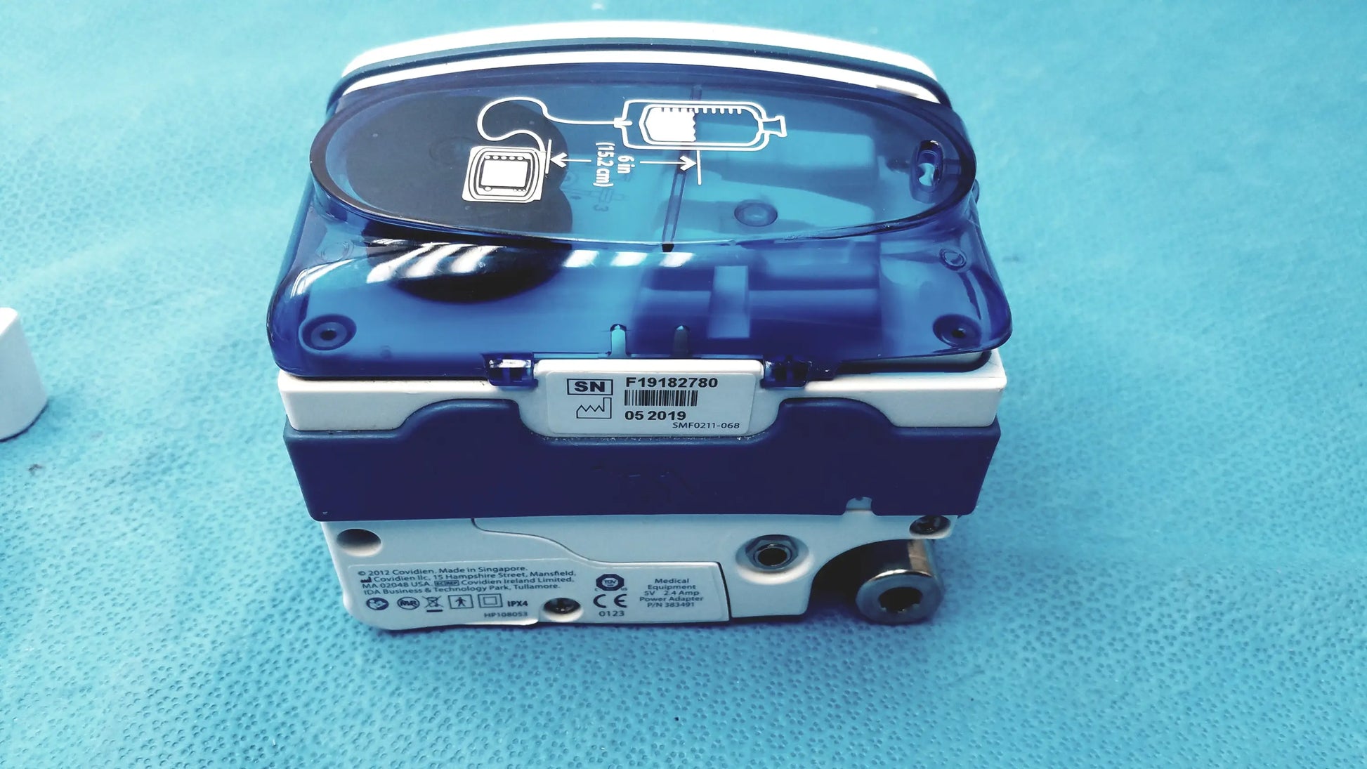 Blue and white covidien kangaroo joey enteral feed and flush pump with transparent lid and pole clamp shown