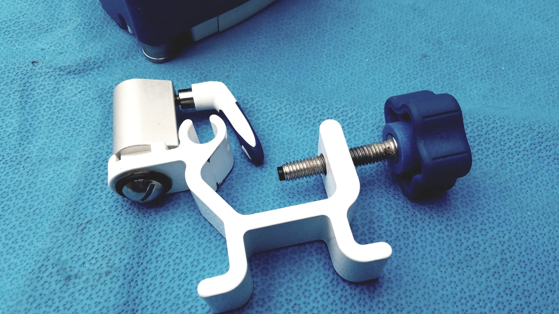 White plastic surgical instrument holder with blue knob and metallic screw for kangaroo joey flush pump pole clamp