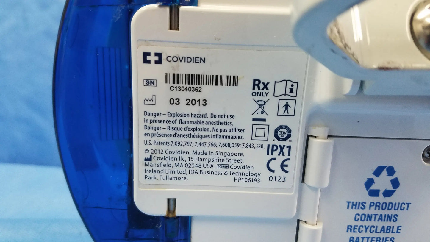 White plastic label with covidien logo and black text on the back of a nutrition feeding pump with barcode and serial number