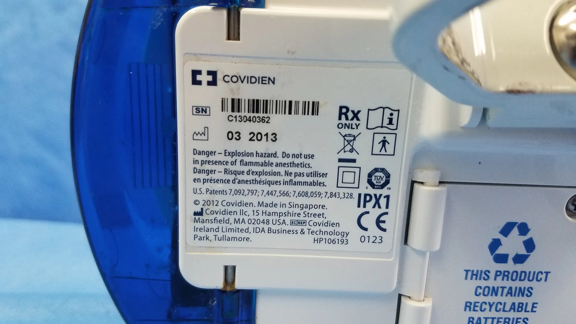 White plastic label with covidien logo and black text on the back of a nutrition feeding pump with barcode and serial number