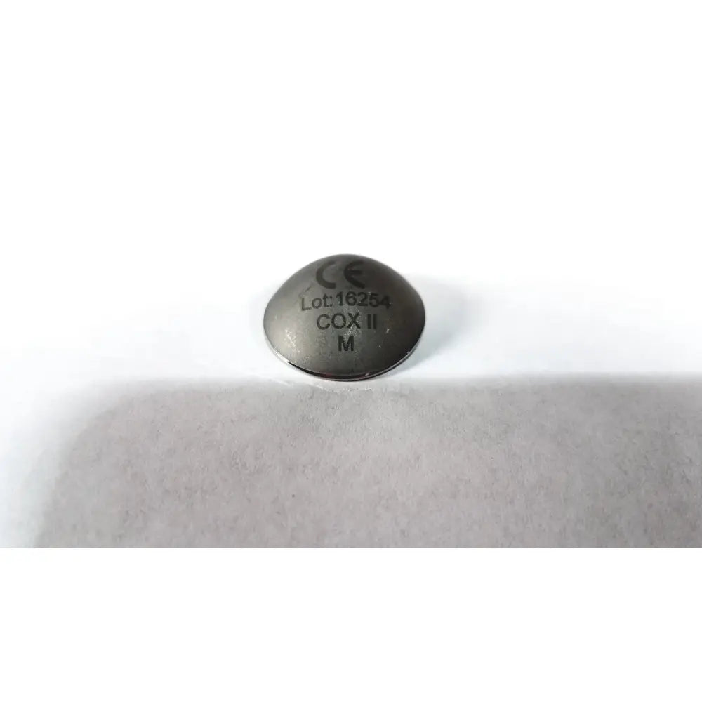 A metallic circular cox ii ocular laser eye shield tablet with matte finish and engraved markings for surgical use