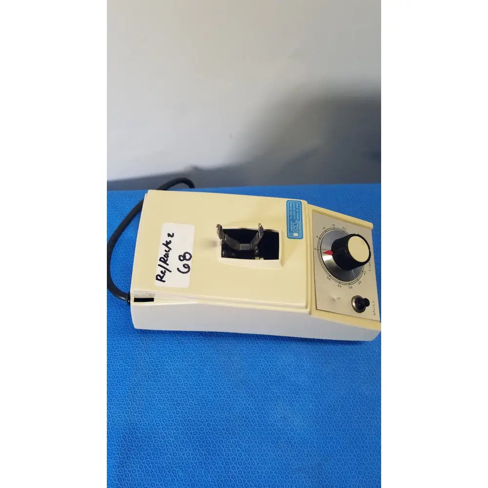 Cream-colored crescent dental wig-l-bug amalgamator with black rotary knob and slot for inserting components