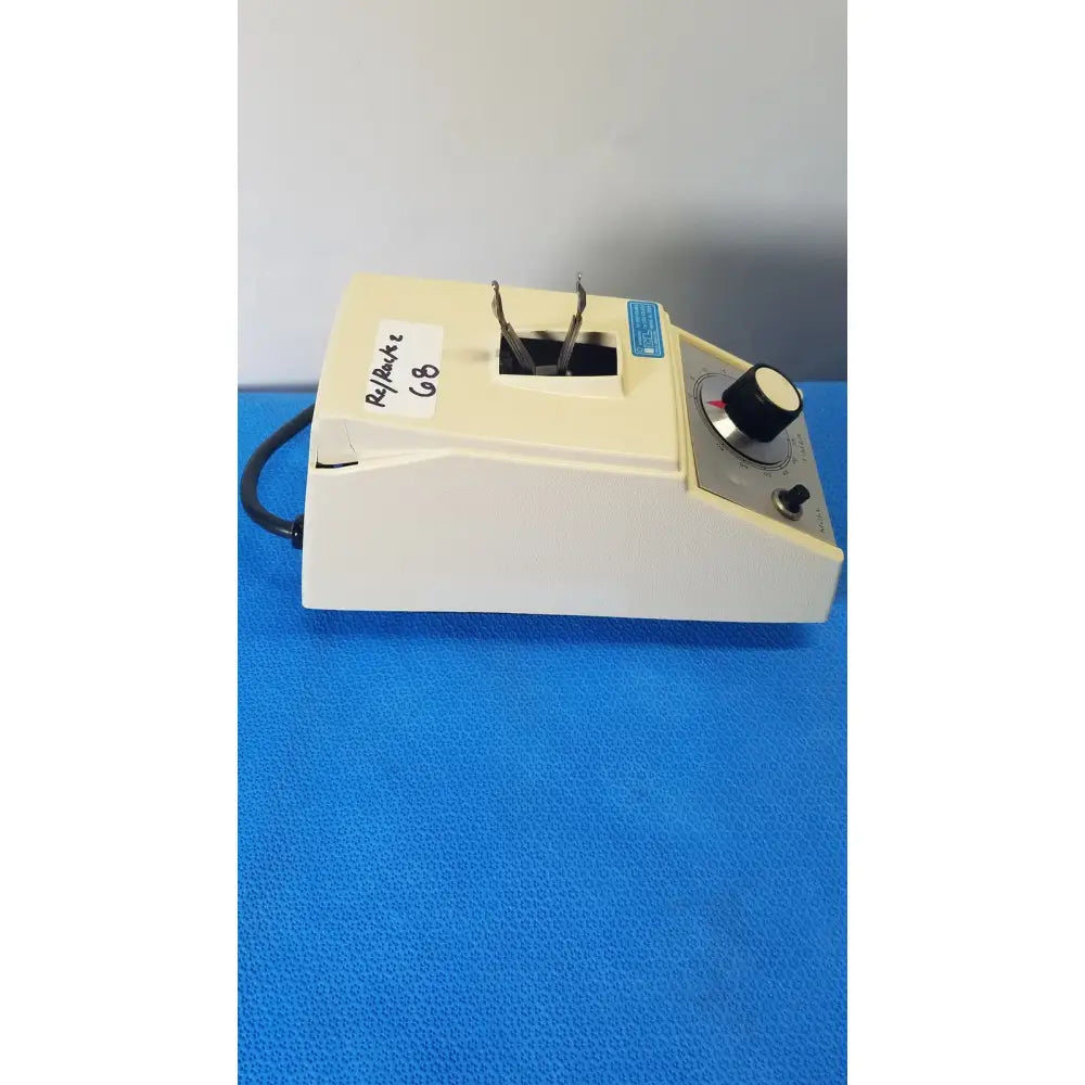 Cream-colored crescent dental wig-l-bug amalgamator with black rotary knob and metal clamps for dental use