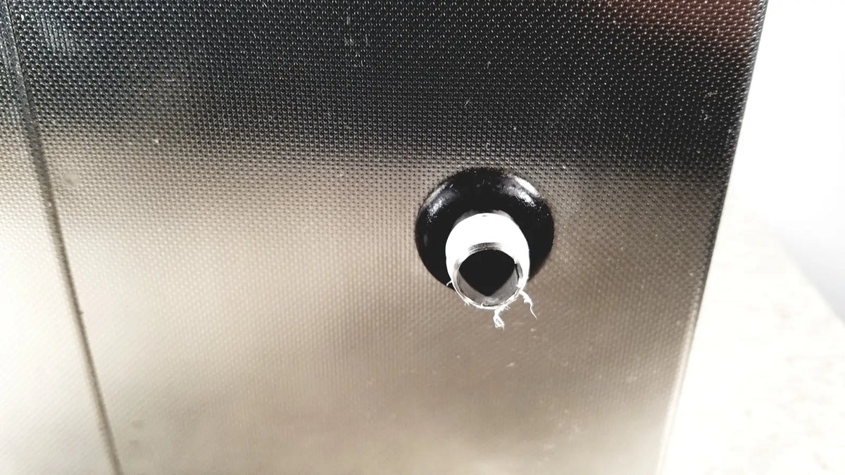 Black rubber grommet with white inner ring set into textured metallic surface of crest ultrasonic powersonic cleaner model p1100d