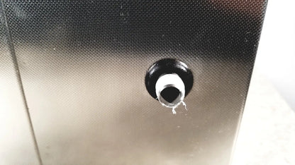 Black rubber grommet with white inner ring set into textured metallic surface of crest ultrasonic powersonic cleaner model p1100d