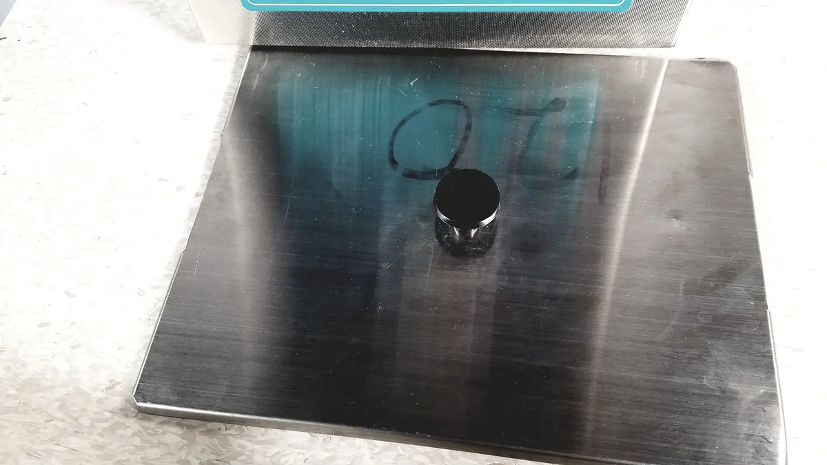 Black cylindrical magnet resting on brushed stainless steel surface of crest ultrasonic powersonic cleaner model p1100d