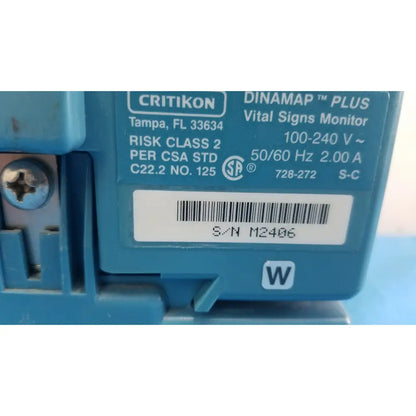 Blue plastic critikon dinamap plus vital signs monitor with white label showing serial number and specifications