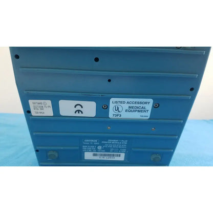 Blue plastic printer module with labels and certification stickers on back of critikon dinamap plus vital signs monitor 8726 rad