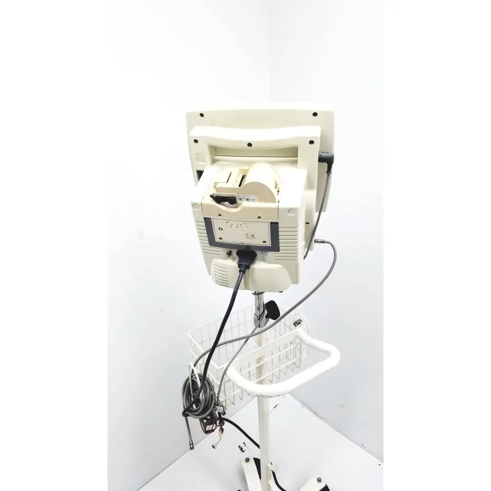 Cream-colored csi criticare 8100 series poet plus vital signs patient monitor mounted on white rolling cart with wire basket