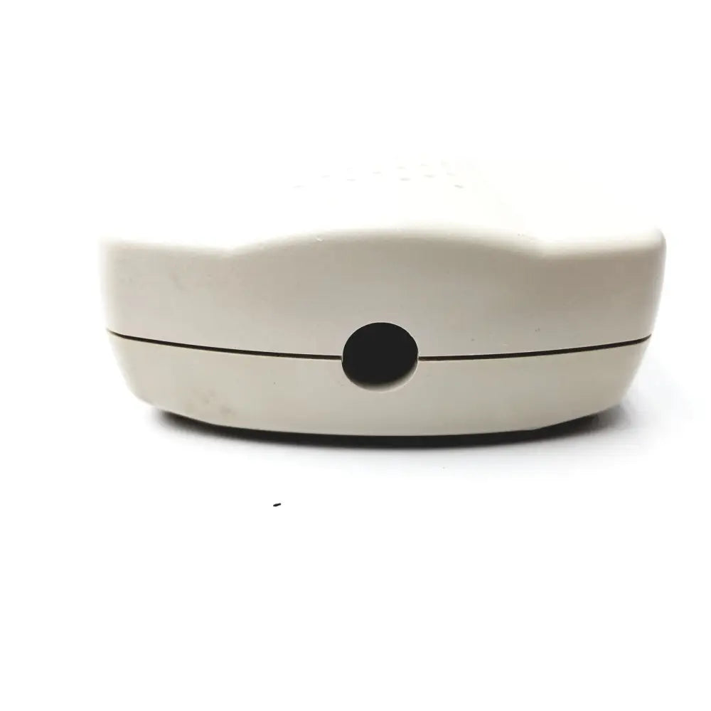Cream-colored plastic gen iii analog curbell patient pillow speaker with rounded rectangular shape and central circular opening