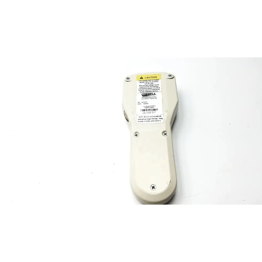 Off-white plastic curbell gen iii analog patient pillow speaker back with yellow caution label and black text