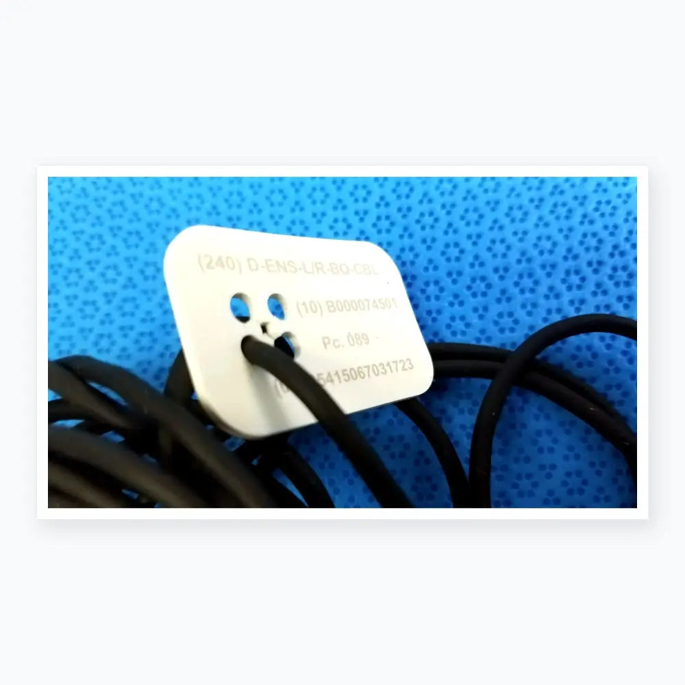 White rectangular label with rounded corners and alphanumeric codes on catheter connector cable for medical equipment reuse