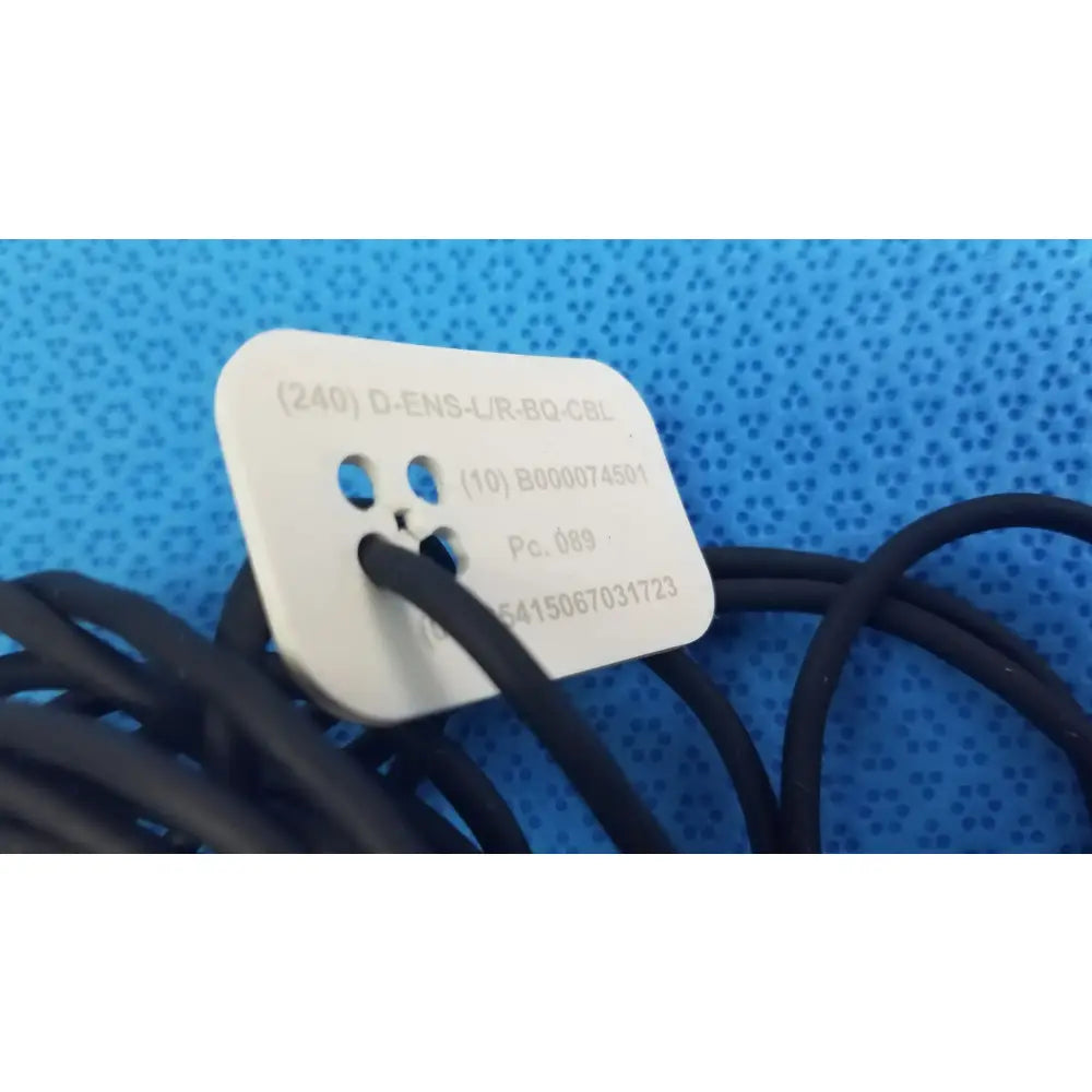 White rectangular label with rounded corners and alphanumeric codes on catheter connector cable for medical equipment reuse