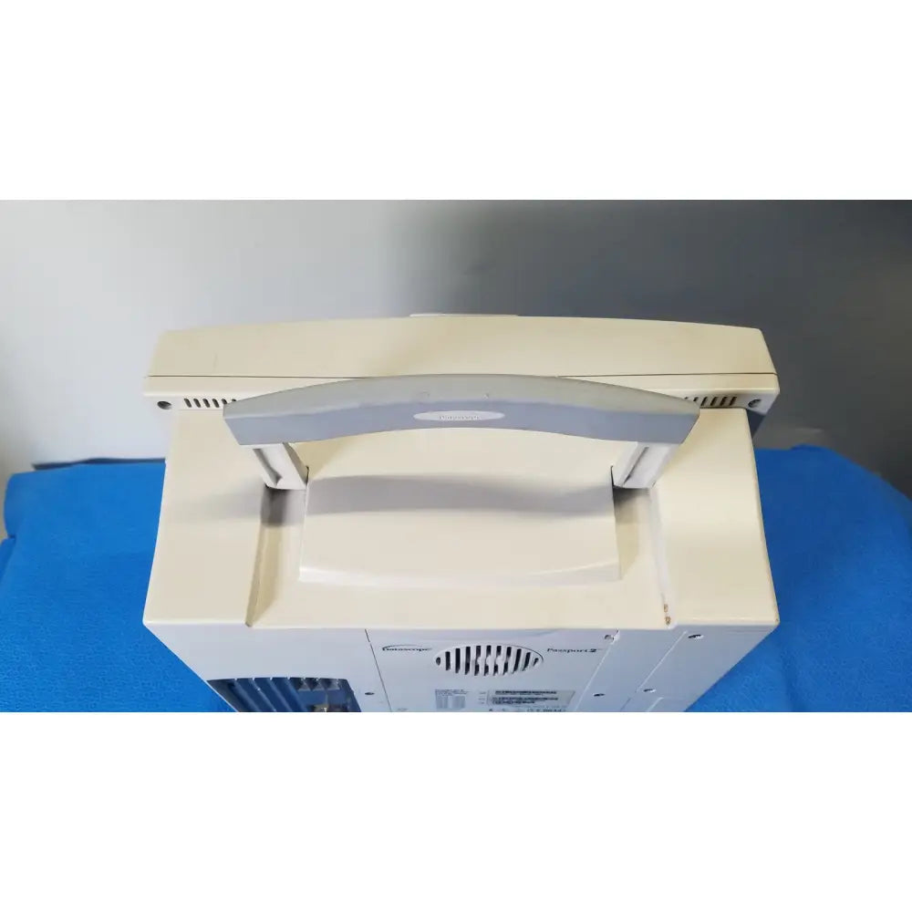 Beige Datascope Passport 2 ECG NIBP EKG patient monitor with gray handle and ventilation grilles on the sides
