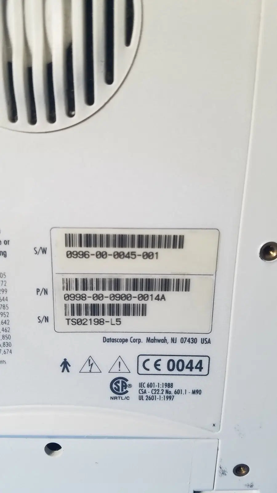 White plastic label with black barcode and datascope corp manufacturer on the back of an ekg patient monitor