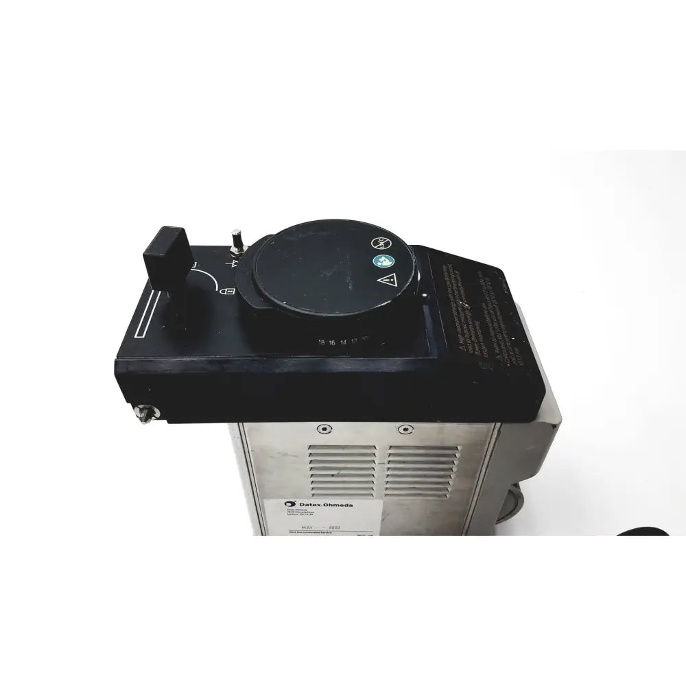 Black control panel with circular dial and toggle switch on silver base of datex ohmeda tec 6 desflurane anesthesia vaporizer
