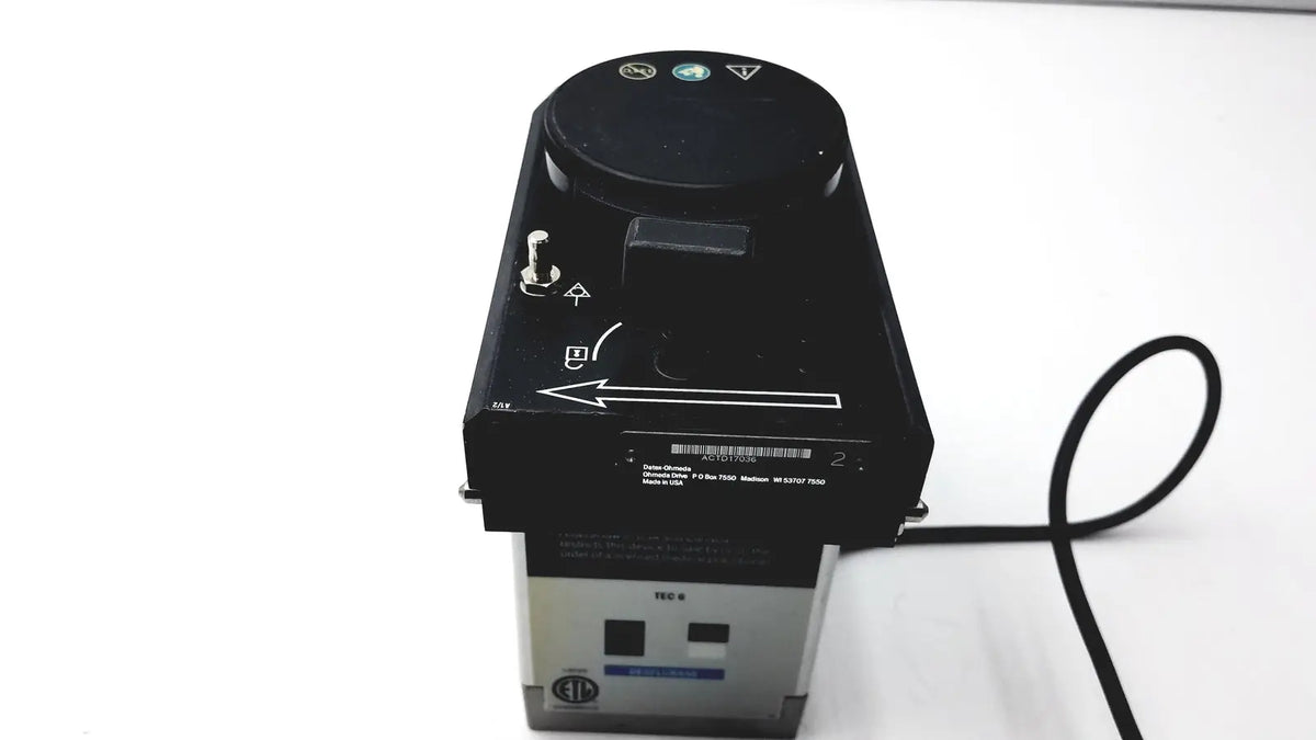 Black and silver industrial-grade Datex Ohmeda TEC 6 desflurane anesthesia vaporizer with circular control dial on top