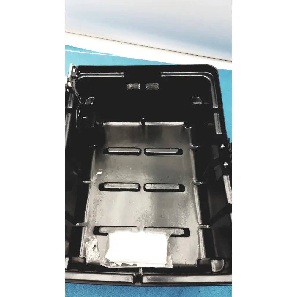 Black plastic underbody tray with molded compartments and metallic insert for defibrillator storage cabinet wall mount
