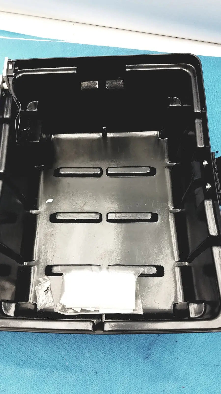 Black plastic tray with metallic silver insert and rectangular cutouts for defibrillator storage cabinet wall mount