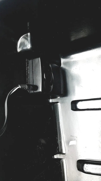 Black rectangular defibrillator storage cabinet with coiled cable and metallic accents for wall mount use