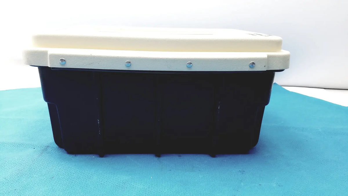 Black plastic defibrillator storage cabinet wall mount with cream-colored lid secured by four silver screws