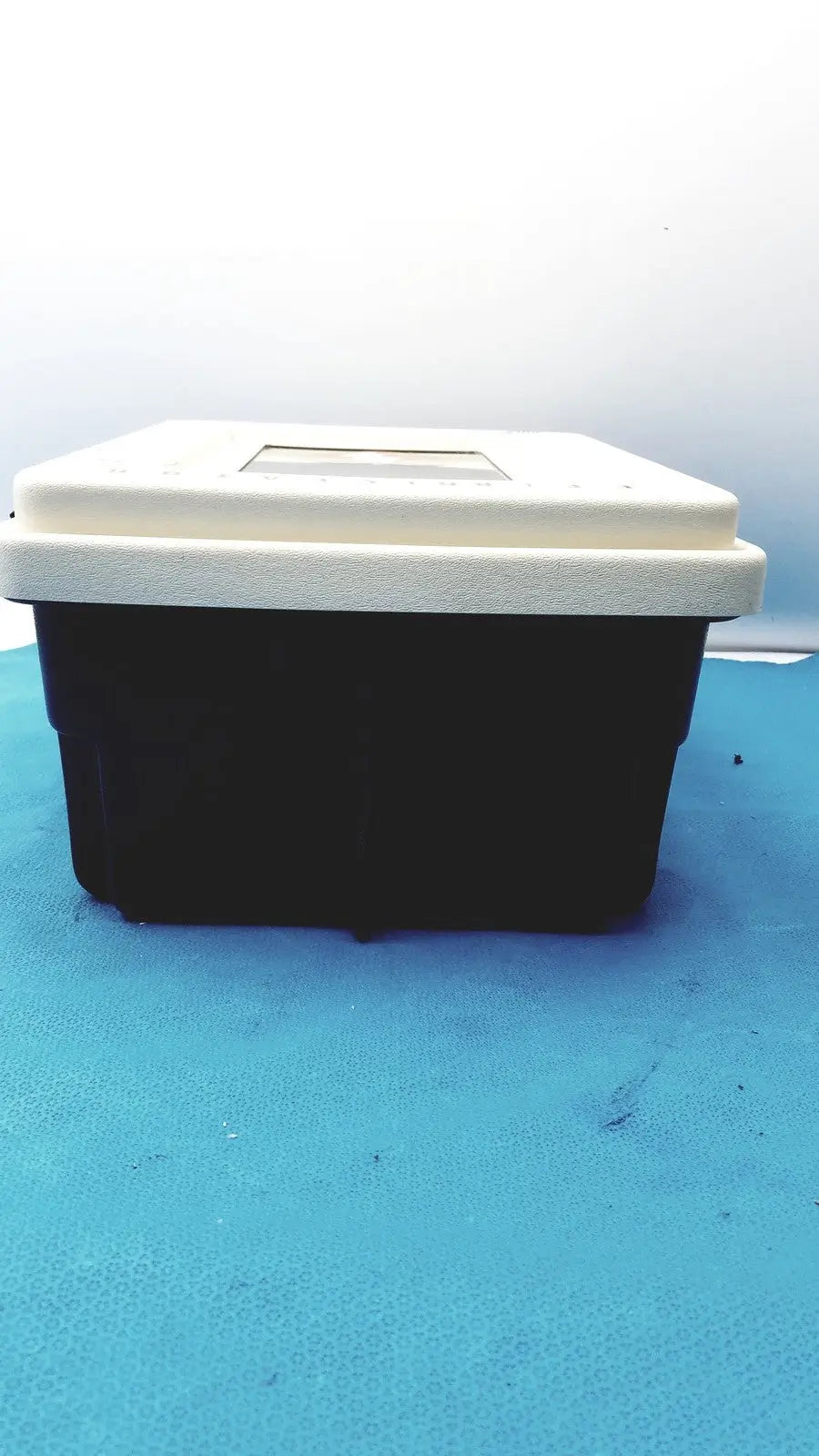 Black and white plastic defibrillator storage cabinet wall mount with rectangular transparent window on the lid
