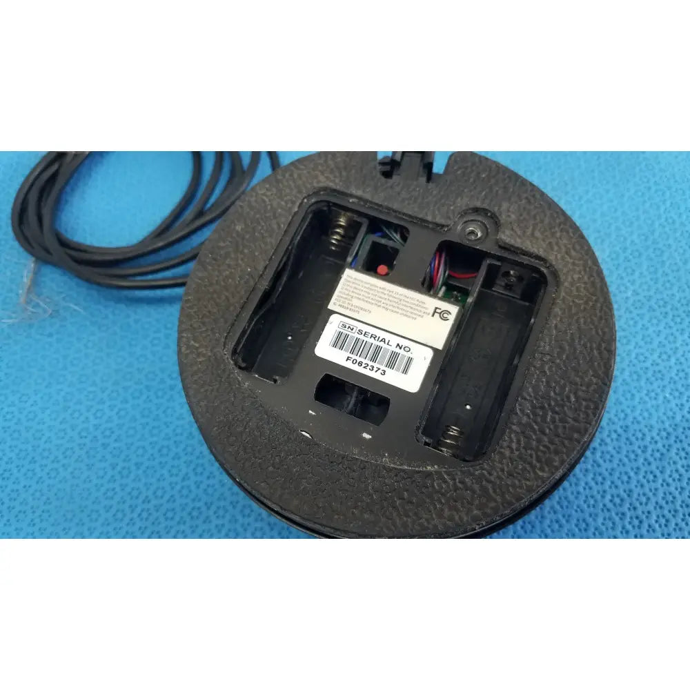 Black circular dentsply cavitron foot control mouse with textured rubber surface and exposed internal wiring serial no f062373