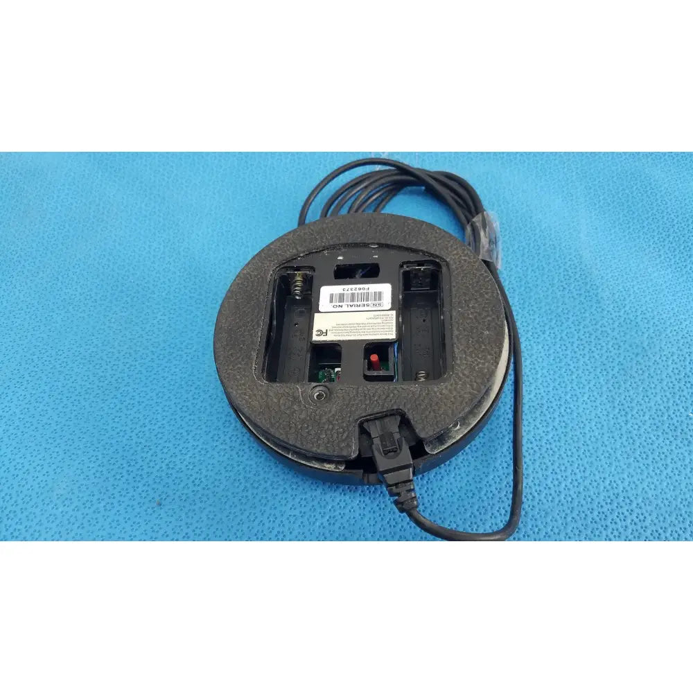 Black dentsply cavitron foot control mouse with textured rubber surface and visible battery compartment plugged in