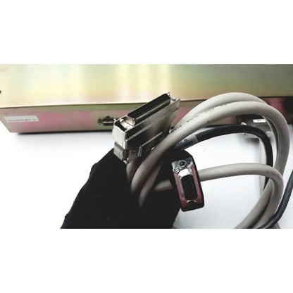 Gray and black industrial cable with metallic d-sub and db-9 serial port on the back of dickinson facs loader electronics interface module