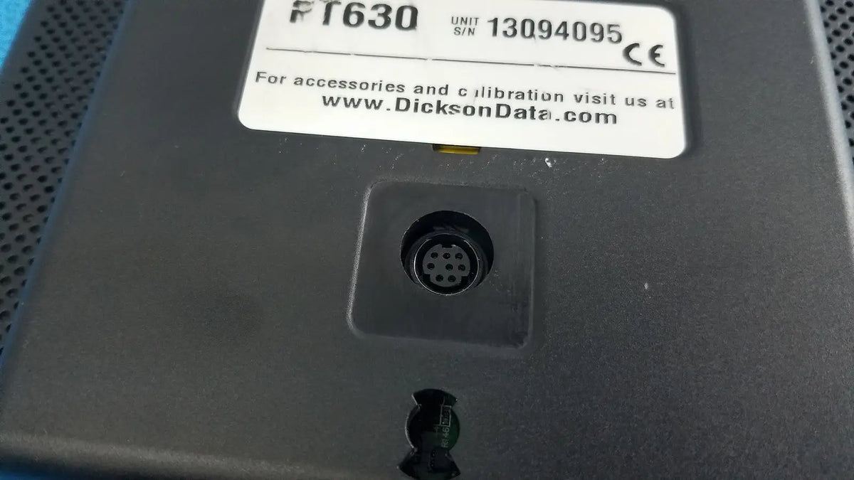 Black plastic dickson data logger model ft630 with white label and circular connector port on the back side